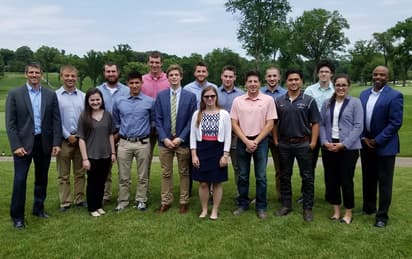 A group of students with High executives smiles for the camera.